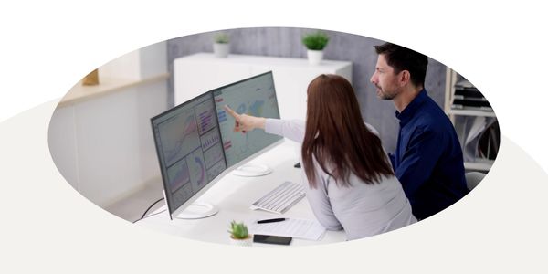 Graphic of a woman pointing to a chart on the computer with a man watching, in a circular frame on a white and tan background.