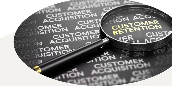 Graphic of the words customer acquisition and retention repeated, with customer retention in yellow highlighted by a magnifying glass, in a circular frame with a white and tan background.